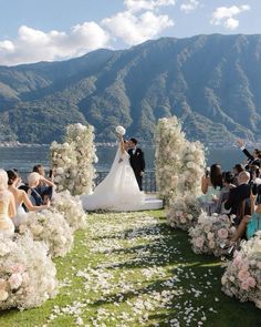 a bride and groom standing in front of an outdoor ceremony with flowers on the grass