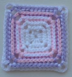 a crocheted square is shown in pastel pink, purple and white colors