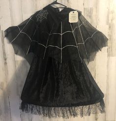 a black dress with spider webs on it and a tag hanging from the back