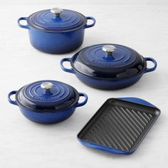 three blue cast iron pots and one with a griddle on the side, sitting next to each other