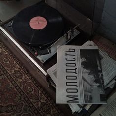 an old record player sitting on top of a table next to some papers and magazines