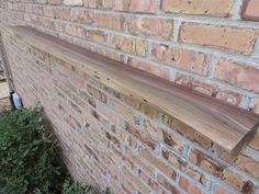 a wooden shelf on the side of a brick wall