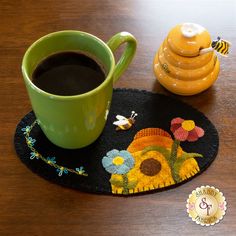 a cup of coffee sitting on top of a wooden table next to a yellow bee