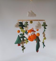 a mobile made to look like a fox hanging from a tree with leaves and clouds