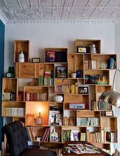 a living room filled with furniture and bookshelves next to a wall mounted lamp