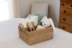 a basket filled with baby items sitting on top of a bed next to a dresser