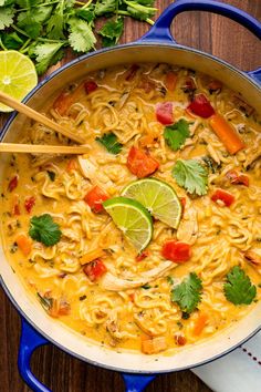 a blue pot filled with noodles and lime wedges on top of a wooden table