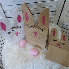 three paper bags with bunny ears are sitting on a white fur covered floor next to some pink balls