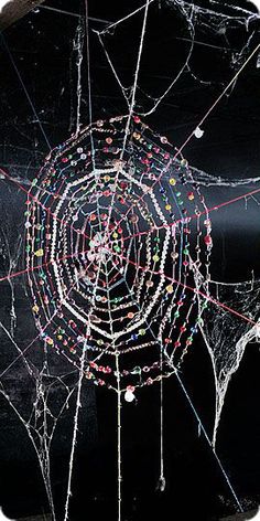 the spider web is covered in many different colored beads on it's black surface