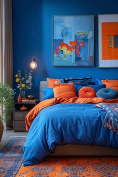 a bedroom with blue walls and orange bedding in the center, two paintings on the wall