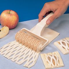 a person is using a brush to cut out pieces of paper with an apple in the background