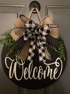 a welcome sign hanging on a door with a bow and ribbon attached to the front