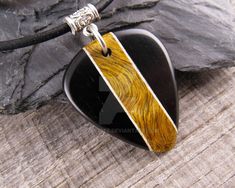 a black and yellow guitar pick pendant on a leather cord