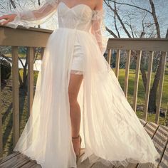 a woman in a white dress standing on a deck