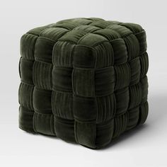 an ottoman made out of green velvet with squares on the top and bottom, sitting in front of a white background