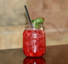 a glass filled with liquid and strawberries on top of a table