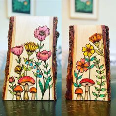 two pieces of wood with flowers painted on them sitting on a table next to each other