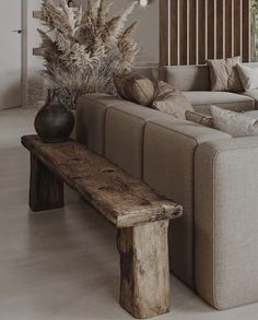 a living room filled with furniture and a large wooden bench next to a vase on top of a table