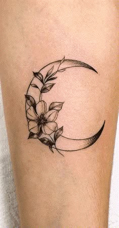 a woman's thigh with a crescent and flowers on it