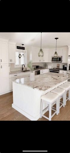 a large kitchen with white cabinets and marble counter tops, an island in the middle