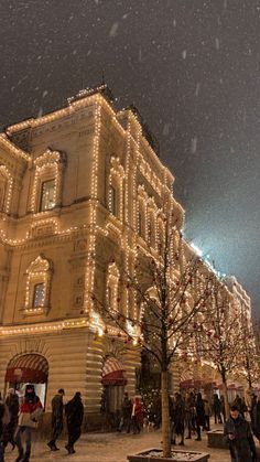 people walking in front of a building with christmas lights on it