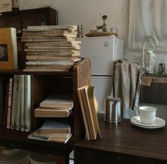 a book shelf filled with lots of books next to a coffee cup and saucer