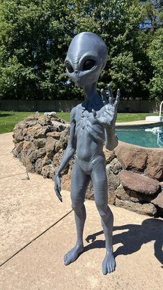 an alien statue standing in front of a swimming pool