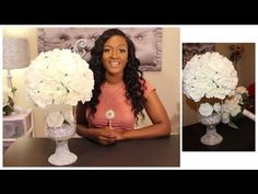 a woman sitting at a table with two vases filled with white flowers in front of her