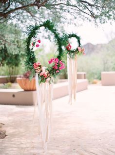 an outdoor ceremony with flowers and greenery in the shape of a heart, hanging from a tree