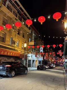 cars parked on the street with red lanterns hanging above them