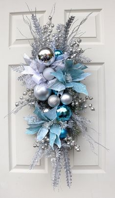 a wreath with blue and silver ornaments hanging on a door