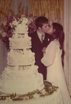 a bride and groom kissing in front of a wedding cake