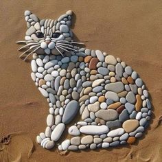 a cat made out of rocks sitting on the sand with it's eyes closed