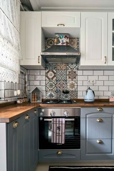 a kitchen with grey cabinets and white tile backsplashes, wood counter tops