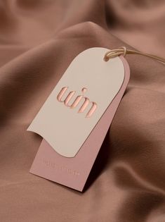 a tag with the letter m on it is laying on a satin material surface,