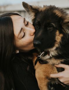 a woman is kissing her dog outside