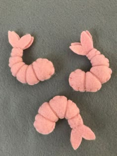 three pieces of pink felt sitting on top of a gray carpet next to each other