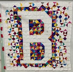 a quilt made to look like the letter b with many different colored triangles on it