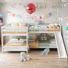 a room with two bunk beds and balloons on the wall, one has a slide in front of it