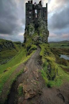 an old castle on top of a hill with a dirt path leading to the entrance