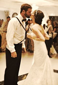 a bride and groom are kissing in front of a group of people on the dance floor