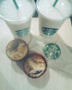 two starbucks drinks and muffins on a table