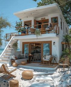 a white house on the beach with lots of furniture and plants in front of it