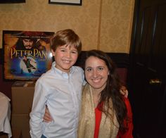 two people standing next to each other in front of a movie poster on the wall