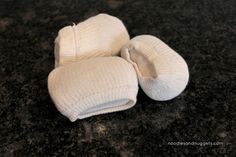 three white knitted mittens sitting on top of a black counter