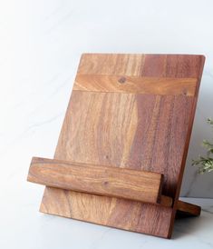 a wooden cutting board sitting on top of a counter next to a vase with flowers