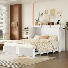 a white bed sitting next to a window in a room with wooden floors and furniture