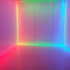 an empty room with colored lights on the walls and floor, in front of a white wall