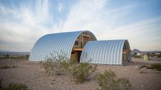 two large metal buildings sitting in the middle of a desert