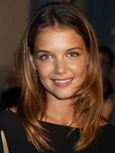 a close up of a person wearing a black dress and smiling at the camera with other people in the background